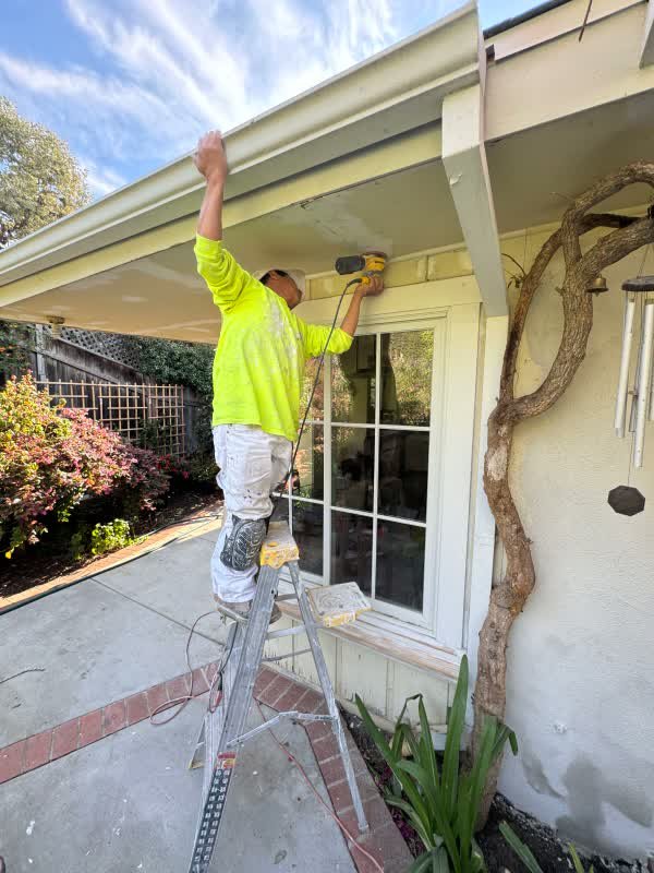 Painter prepping eaves and stucco on a Brentwood home